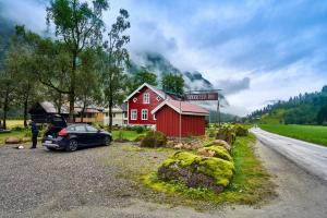 un coche estacionado junto a un granero rojo y una casa roja en Rødseter Gjestegård, en Fjærland