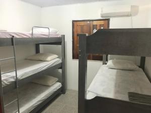 a room with three bunk beds and a mirror at Kitnets da vana in Morro de São Paulo
