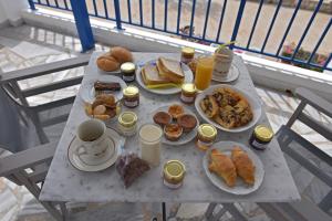 a table with plates of breakfast food on a balcony at Sarris Planet in Ermoupoli