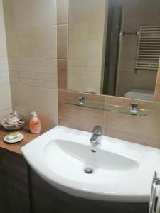 a bathroom with a white sink and a mirror at Słoneczny Apartament I LUX RELAX Apartamenty Kołobrzeg in Kołobrzeg