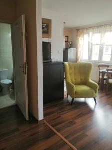 a living room with a yellow chair and a kitchen at Słoneczny Apartament in Kołobrzeg