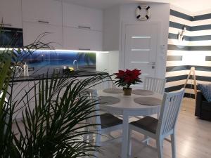 a white kitchen with a white table and chairs at Apartament na Wzgórzu in Mechelinki