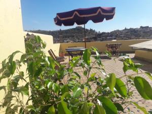 a patio with an umbrella and a table and chairs at Riad Ranya in Fès