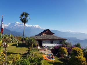 una casa con una palma e montagne sullo sfondo di ES Deurali Resort a Pokhara