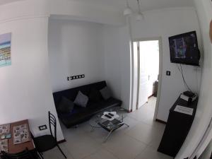 a living room with a black couch and a tv at Luxor appartement in Flic-en-Flac