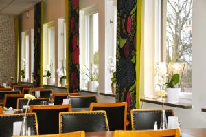 una sala da pranzo con tavoli, sedie e finestre di Sjögestad Motell a Vikingstad