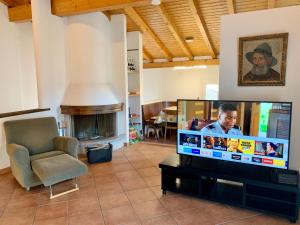a living room with a flat screen tv and a chair at Comano Lugano Ticino - B&B Walterina in Comano