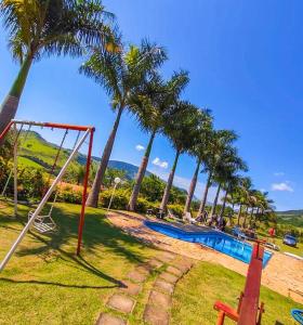 een zwembad met palmbomen en een schommel bij Pousada Caruaru in Socorro