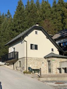 ein weißes Gebäude mit einem schwarzen Dach und einer Bank in der Unterkunft Holiday house Nune in Zreče