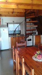 ein Esszimmer mit einem Tisch und eine Küche mit einem Kühlschrank in der Unterkunft Bungalow Montes in El Bolsón