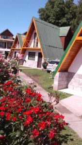 uma casa com flores vermelhas em frente em Bungalow Montes em El Bolsón