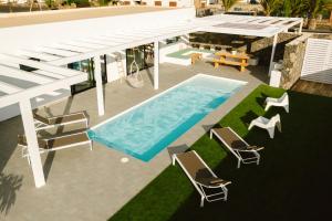 uma vista superior para uma piscina com cadeiras e uma mesa em Casa Los Lajares em Lajares