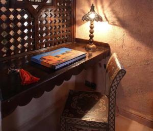 - un bureau avec un livre, une lampe et une chaise dans l'établissement O'Atlas, à El Harkat