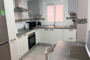 a white kitchen with white cabinets and a table at RENOVATED HOUSE IN OLD TOWN MARBELLA. in Marbella