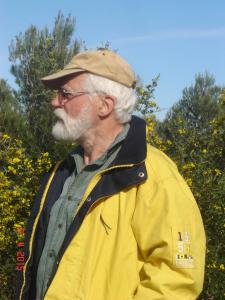 um homem mais velho com um chapéu e um casaco amarelo em La Truite Joyeuse em Saint-Hubert