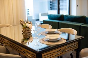 a glass table with plates and wine glasses on it at Silver Fox Residence in Poiana Brasov