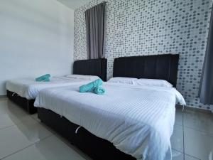 2 bedden in een slaapkamer met witte lakens en blauwe kussens bij Mykey Atlantis D-09-05 Melaka City in Melaka