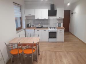 a kitchen with white cabinets and a table and chairs at Apartament Drawsko Pomorskie in Drawsko Pomorskie