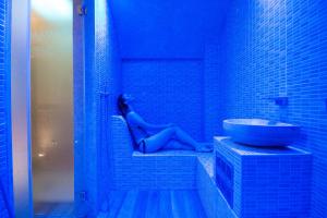 une femme dans une salle de bains bleue avec lavabo dans l'établissement Masseria Grottella, à Avetrana