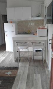 a kitchen with a white counter and two stools at pequeña casa completa en el pinar in El Pinar