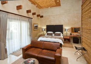 a bedroom with a bed and a leather couch at Surval Boutique Olive Estate in Oudtshoorn