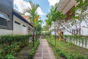 a path between two buildings with palm trees at Lavender Angkor Boutique in Siem Reap