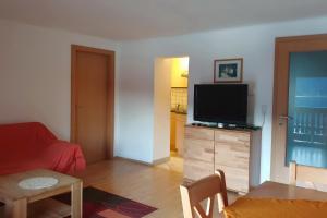 una sala de estar con TV de pantalla plana en una cómoda de madera en Haus am Hang en Innerschwand