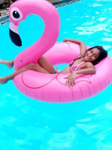 a woman laying on an inflatable flamingo in a pool at Chez nous in Pereybere