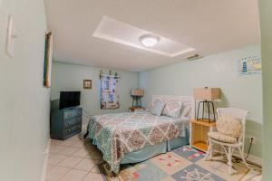 a bedroom with a bed and a tv and a chair at CasaSeaSpell Galveston in Galveston