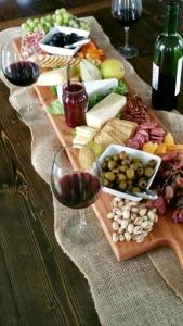 einen Tisch mit einem Tablett mit Speisen und Weingläsern in der Unterkunft Le Chalet, chambres d hôtes, petit déjeuner inclus in Roubion