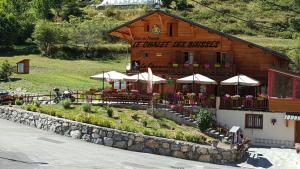 un bâtiment avec des tables et des parasols devant lui dans l'établissement Le Chalet, chambres d hôtes, petit déjeuner inclus, à Roubion