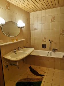 ein Badezimmer mit einem Waschbecken, einer Badewanne und einem Spiegel in der Unterkunft Ferienwohnung Seidl Top 1 in Rauris