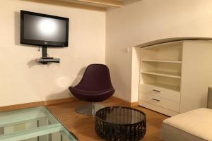 ein Wohnzimmer mit einem Stuhl und einem TV an der Wand in der Unterkunft La casina in Burlamacchi in Mailand