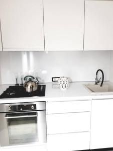 a white kitchen with a stove and a sink at Trakų street Apartment in Šiauliai