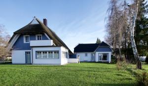 a white house with a thatched roof at Haus Meerblau in Born