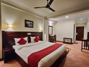 a bedroom with a large bed with red pillows at Bandipur Village Inn in Bandipur