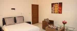 a bedroom with a bed and a chair and a table at Villa Mariam in Bamako