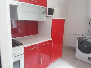 una cucina con armadi rossi e una lavatrice di les mouettes a Plérin