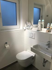 a white bathroom with a toilet and a sink at Stilvolles Studio in Osnabrück