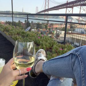 una persona che tiene in mano un bicchiere di vino bianco di Tram House @ Lx Factory! a Lisbona