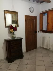 ein Zimmer mit einer Blumenvase auf einer Kommode und einer Uhr in der Unterkunft CASA SERENA UNO - CENTRO STORICO in Montepulciano