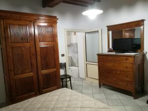 ein Schlafzimmer mit einer Holzkommode und einem TV auf einer Kommode in der Unterkunft CASA SERENA UNO - CENTRO STORICO in Montepulciano
