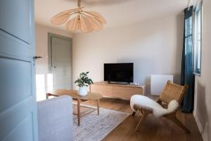 een woonkamer met een televisie en een tafel en stoelen bij Le cocon de Jules in Colmar