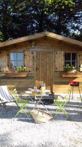 a cabin with a table and chairs in front of it at Le Chalet du Clos Giot in Saint-Vaast-la-Hougue