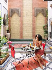 Eine Frau, die an einem Tisch auf einer Terrasse sitzt in der Unterkunft Riad Tamarrakecht in Marrakesch