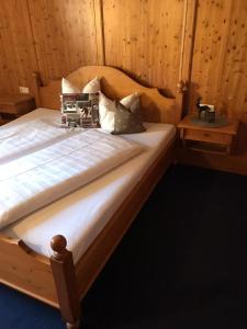 uma cama com lençóis brancos e almofadas num quarto em Appartement Scherrhof em Kirchberg in Tirol