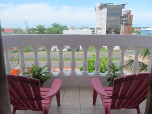 uma varanda com cadeiras cor-de-rosa e vista para uma rua em Easy Inn Hotel em Cidade de Belize