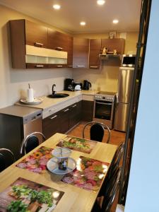 una cocina con mesa de madera con sillas y una cocina con electrodomésticos de acero inoxidable. en Grau Apartments 26, en Pärnu