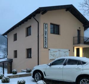 un coche blanco estacionado frente a un edificio en Pensiunea Exedra, en Borşa