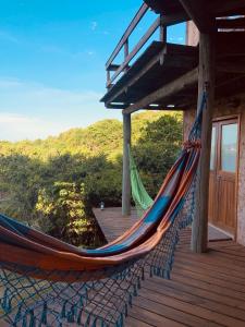 a hammock on the deck of a house at Villa California in Praia do Rosa